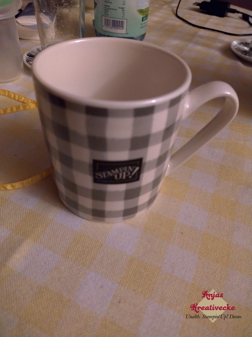 Eine grau-weiß-karierte Tasse mit Stampin' Up!-Logo auf einem Tisch