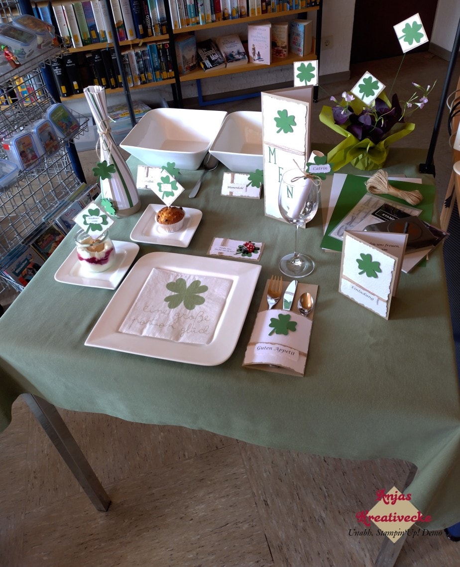 Ein grün eingedeckter Tisch mit Tellern und Gläsern. Alles verziert mit grünen Kleeblättern.