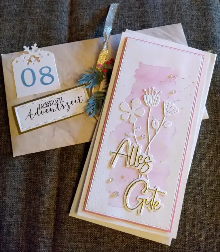 Kreativprojekte Adventskalendertausch Karte in DIN lang mit gewischtem rosafarbenem Hintergrund. Darauf Blüten in weiß mit Spruch "Alles Gute" in weiß und gold. Im Hintergrund ein Umschlag mit goldenem Band und Zweig mit roten Beeren mit Spruch "Zauberhafte Adventszeit". Gestaltet von Katrin