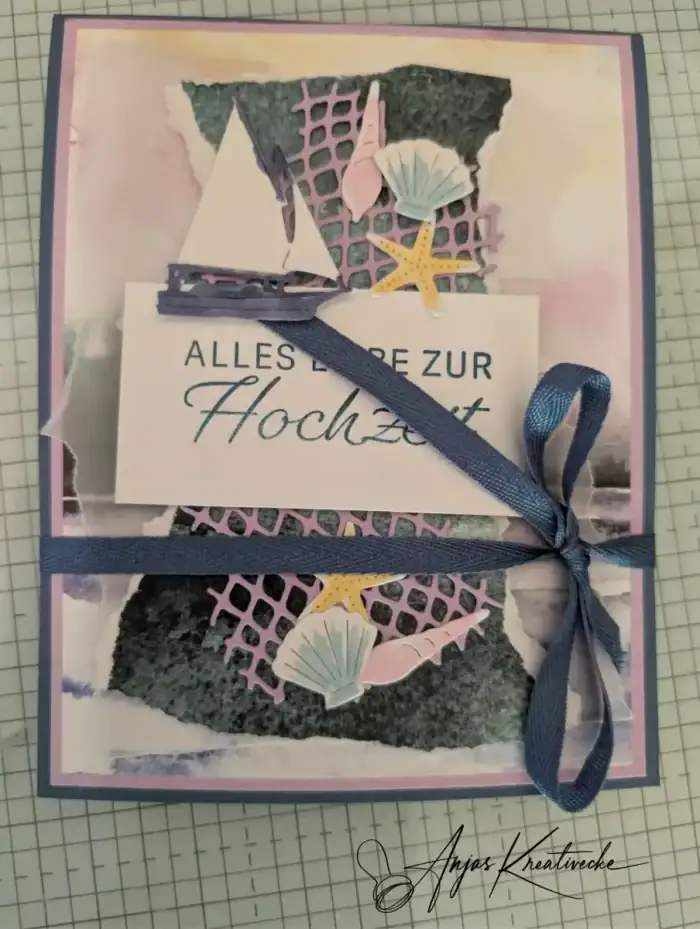 Selbstgestaltete Hochzeitskarte mit Segelboot, Muscheln und Seestern in Rosa und Marineblau, verziert mit Stoffband und dem Schriftzug „Alles Liebe zur Hochzeit"